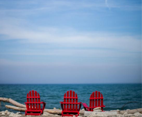 Red adirondack chairs overlooking the lake.